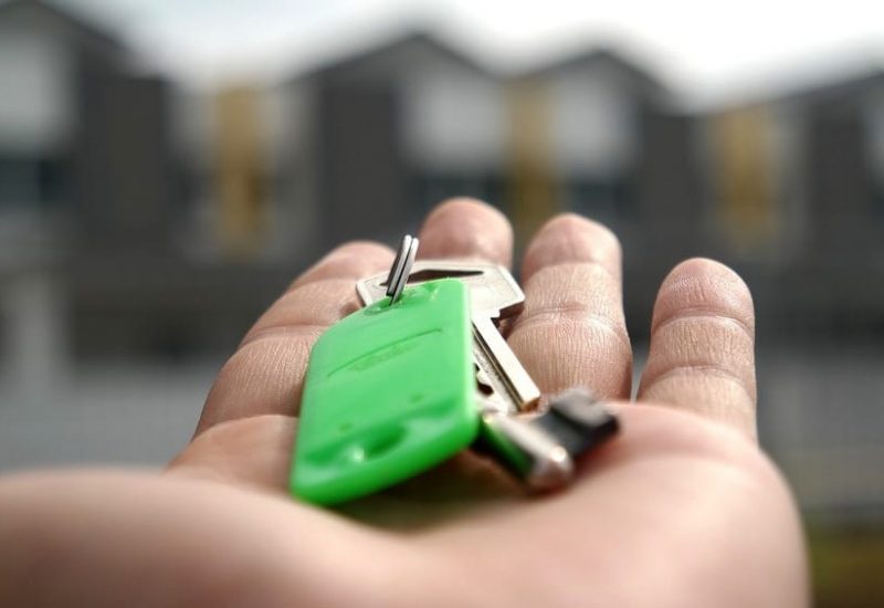 Une main tient des clés devant des maisons